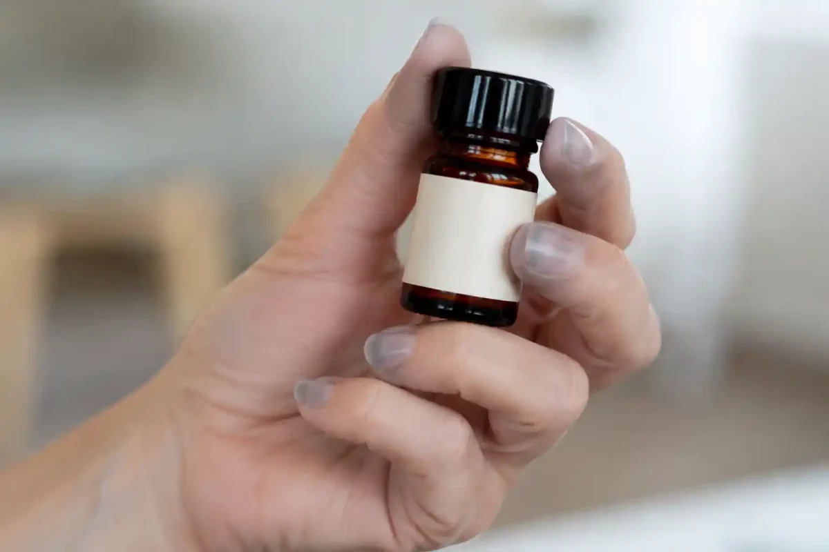 Main aux doigts légèrement bleus tenant un flacon de poppers